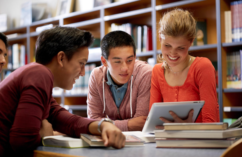 Three teens studying over laptop