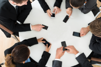 Business people sitting around the table with cell phones