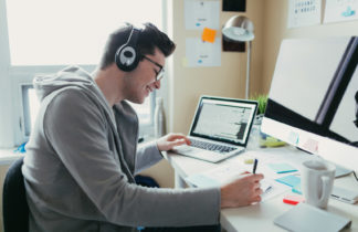 Male college student wearing headphones working on his laptop